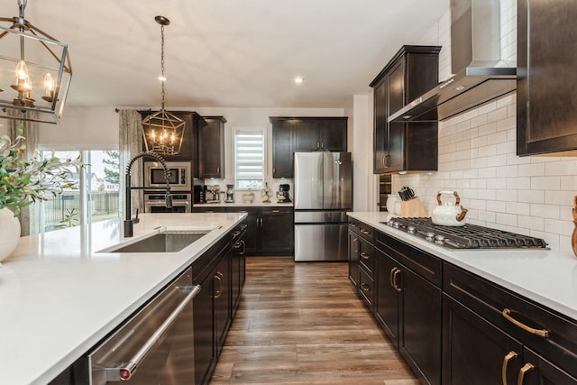 kitchen with sink, decorative light fixtures, stainless steel appliances, wall chimney exhaust hood, and dark brown cabinets