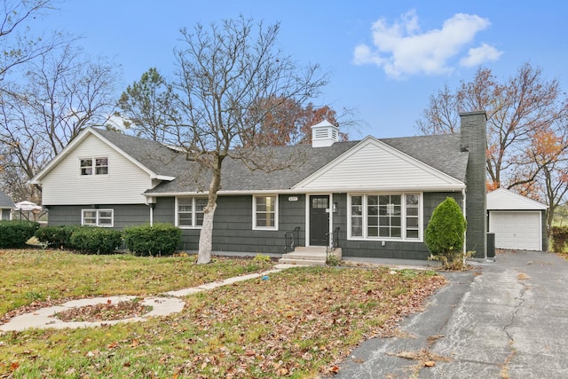 view of front of house featuring a garage, an outbuilding, and a front lawn