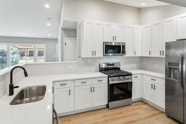 kitchen featuring backsplash, sink, white cabinets, and appliances with stainless steel finishes