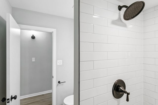 bathroom featuring a tile shower, toilet, and hardwood / wood-style floors