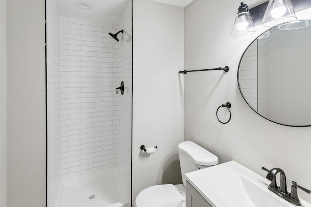 bathroom with a tile shower, vanity, and toilet