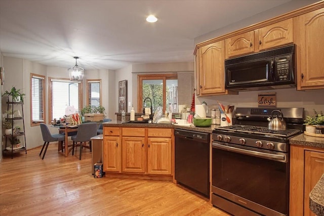 kitchen with light hardwood / wood-style flooring, an inviting chandelier, black appliances, and sink