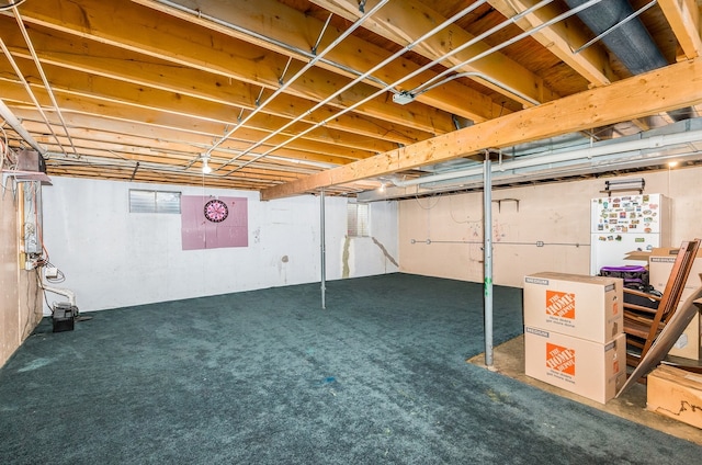 basement with white fridge and dark colored carpet