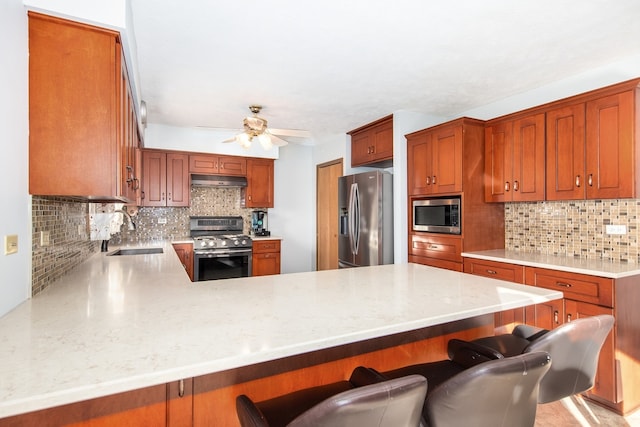 kitchen with stainless steel appliances, sink, kitchen peninsula, backsplash, and a breakfast bar