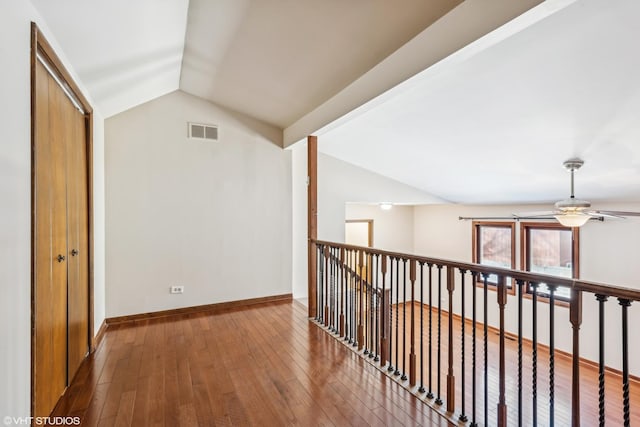 hall with wood-type flooring and vaulted ceiling