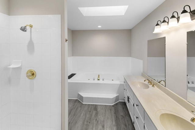 bathroom with vanity, wood-type flooring, tiled bath, and a skylight