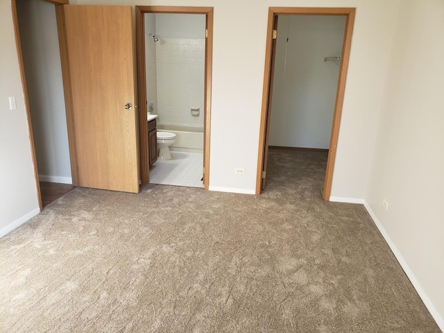 unfurnished bedroom featuring carpet, ensuite bathroom, a closet, and a walk in closet