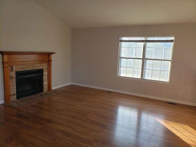 unfurnished living room with vaulted ceiling, a brick fireplace, and hardwood / wood-style floors