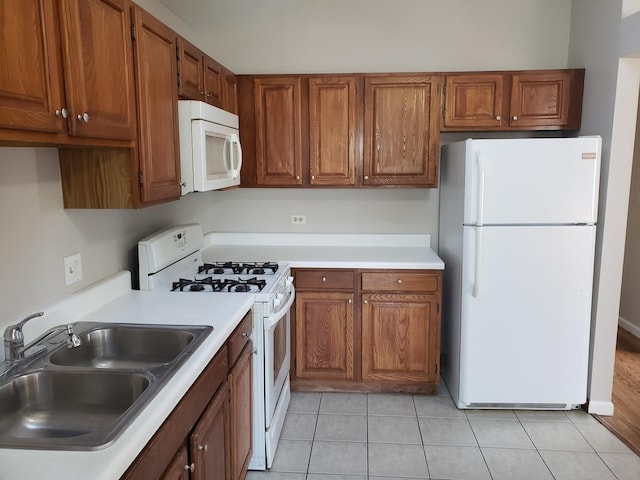 kitchen with light tile patterned floors, sink, and white appliances