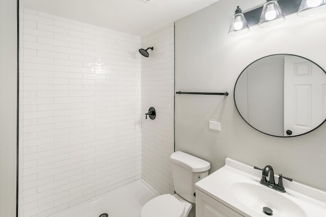 bathroom with vanity, toilet, and tiled shower