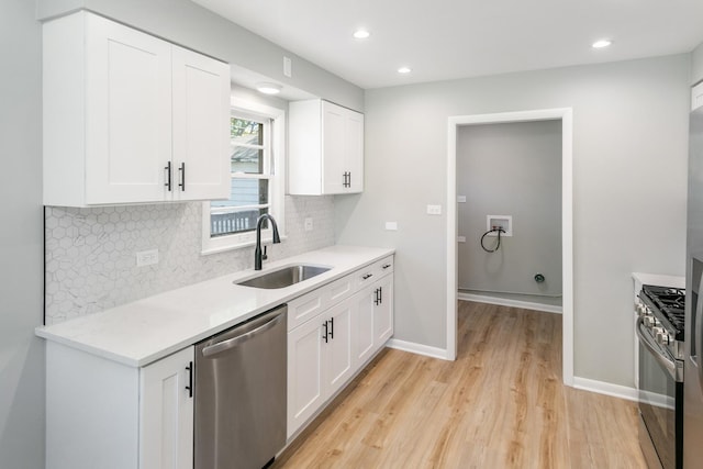 kitchen featuring white cabinets, sink, decorative backsplash, light wood-type flooring, and appliances with stainless steel finishes