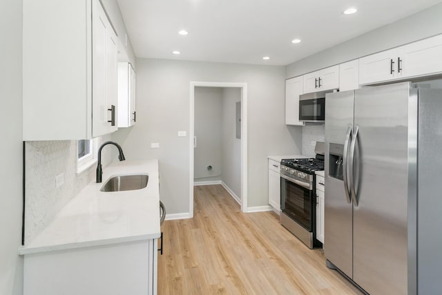 kitchen with sink, light hardwood / wood-style flooring, tasteful backsplash, white cabinetry, and stainless steel appliances