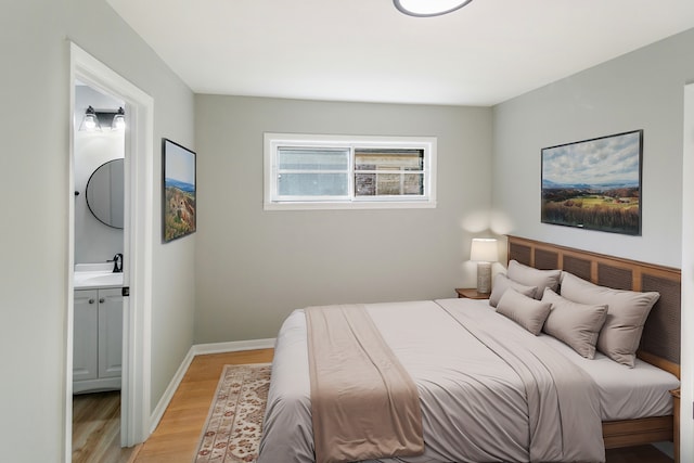 bedroom with ensuite bathroom, sink, and light hardwood / wood-style flooring