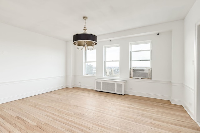 empty room featuring light hardwood / wood-style floors, radiator, and cooling unit