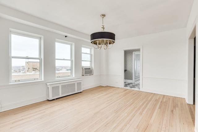 unfurnished room with radiator, light hardwood / wood-style flooring, cooling unit, and a chandelier