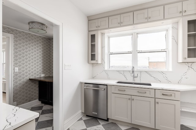 kitchen with light stone countertops, sink, stainless steel dishwasher, and plenty of natural light