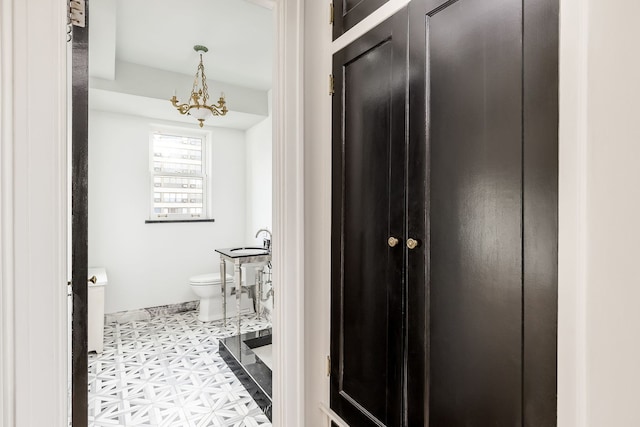 bathroom with tile patterned floors, toilet, a notable chandelier, and sink