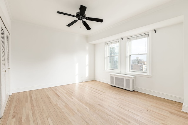 spare room with ceiling fan, crown molding, radiator, and light hardwood / wood-style flooring