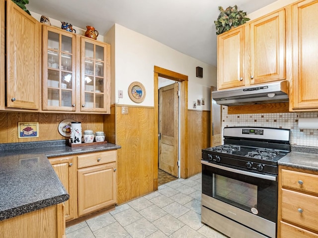 kitchen featuring wood walls, light tile patterned floors, and stainless steel range with gas stovetop