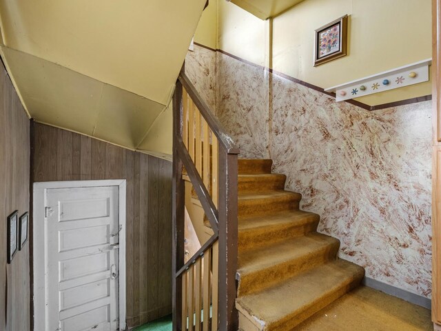 stairway featuring wood walls