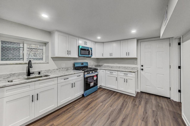 kitchen featuring white cabinets, sink, dark hardwood / wood-style floors, light stone countertops, and appliances with stainless steel finishes