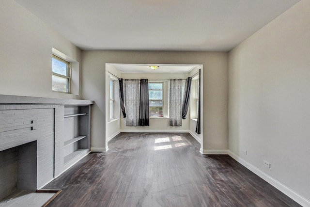 unfurnished living room with dark hardwood / wood-style floors and a brick fireplace