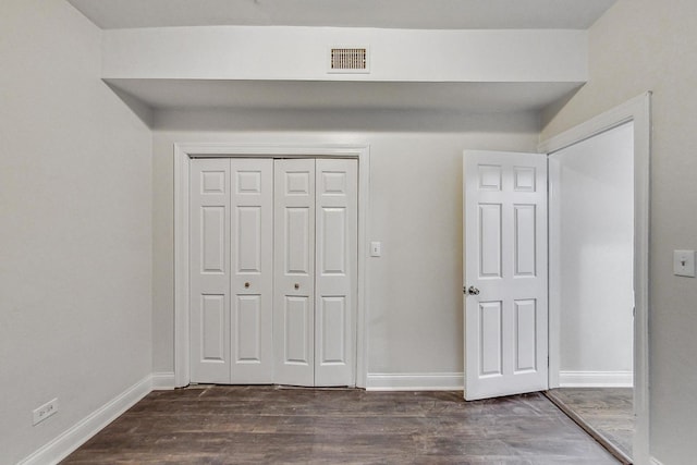 unfurnished bedroom featuring dark hardwood / wood-style flooring and a closet