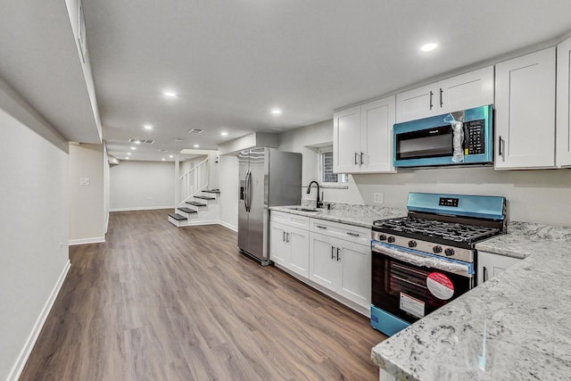 kitchen with light stone countertops, white cabinetry, sink, stainless steel appliances, and dark hardwood / wood-style flooring