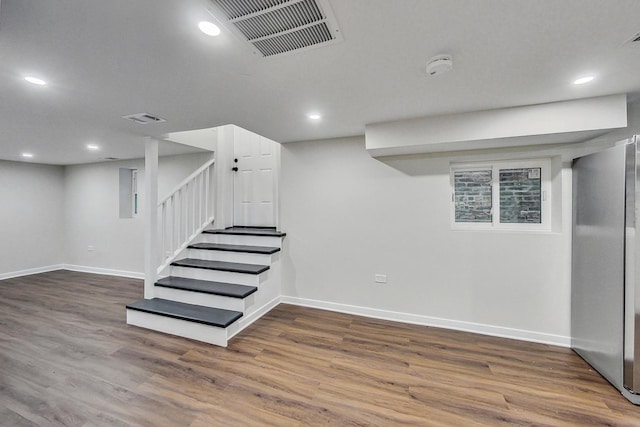 basement featuring stainless steel fridge and dark wood-type flooring