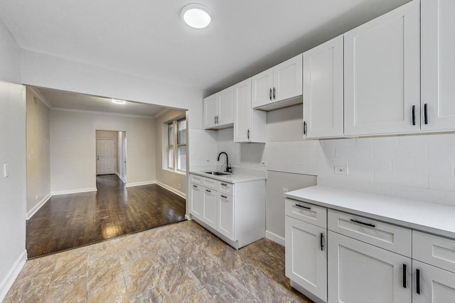 kitchen with tasteful backsplash, sink, white cabinets, and ornamental molding