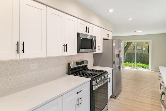 kitchen with white cabinets, light hardwood / wood-style floors, backsplash, and appliances with stainless steel finishes