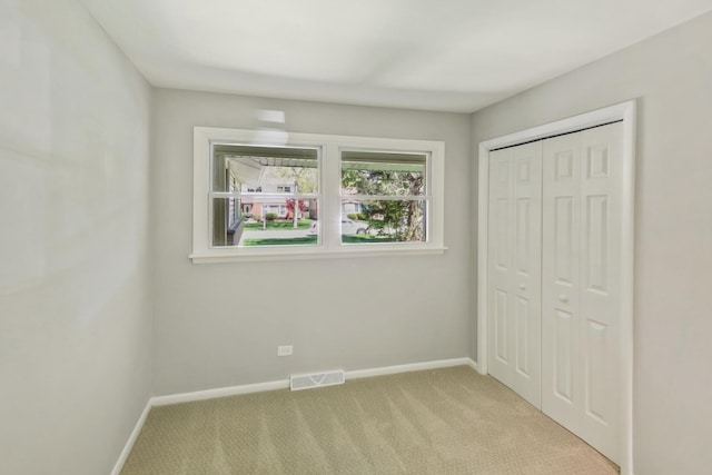 unfurnished bedroom with a closet and light colored carpet