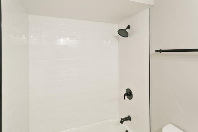 details with tiled shower / bath combo and toilet