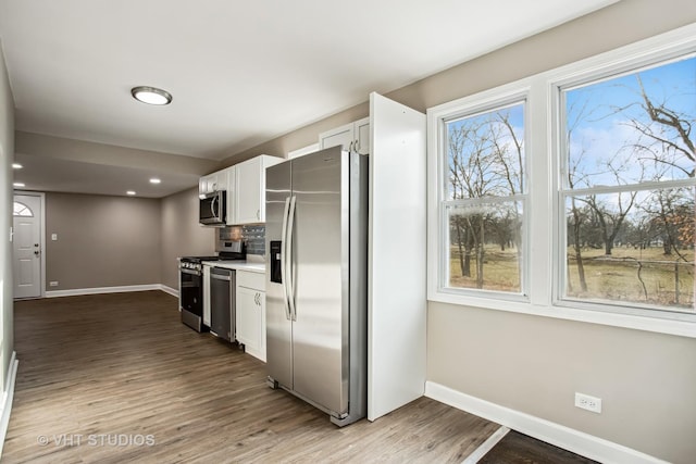 kitchen with decorative backsplash, hardwood / wood-style floors, white cabinets, and stainless steel appliances