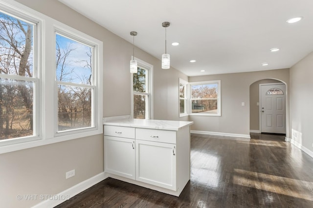 kitchen with decorative light fixtures, white cabinetry, kitchen peninsula, and dark wood-type flooring