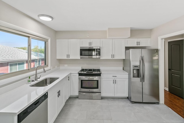 kitchen with white cabinets, light tile patterned floors, stainless steel appliances, and sink