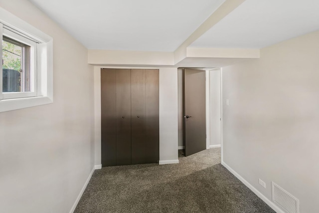 unfurnished bedroom featuring a closet and dark colored carpet