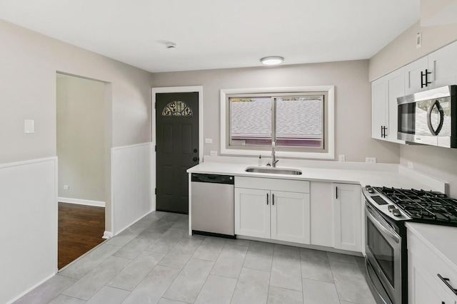 kitchen featuring sink, white cabinets, light tile patterned flooring, and appliances with stainless steel finishes