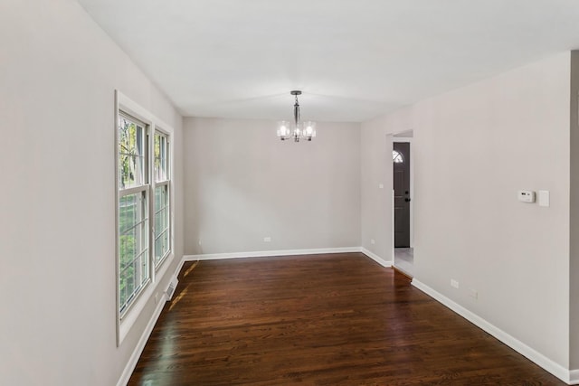 unfurnished room featuring a notable chandelier and dark hardwood / wood-style floors