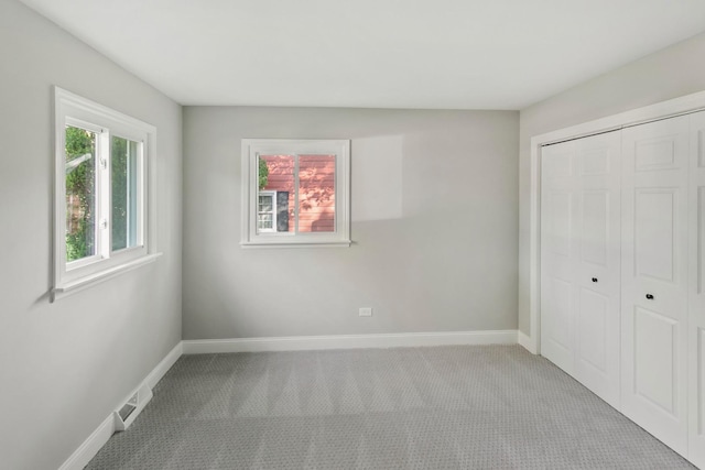 unfurnished bedroom featuring light colored carpet and a closet