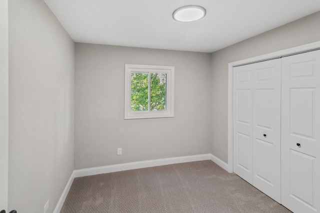 unfurnished bedroom with light carpet and a closet