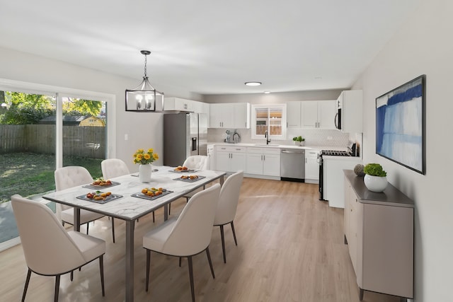 dining area featuring light hardwood / wood-style floors, sink, and an inviting chandelier