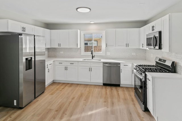 kitchen with light hardwood / wood-style floors, white cabinetry, sink, and appliances with stainless steel finishes