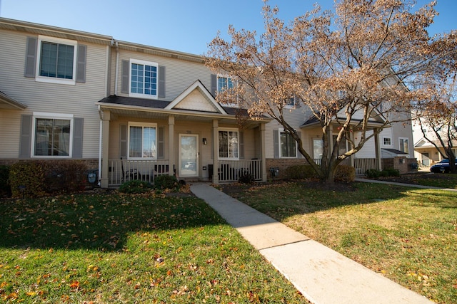 view of property featuring covered porch and a front yard