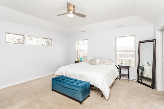 bedroom featuring a raised ceiling, ceiling fan, and light colored carpet