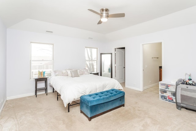 carpeted bedroom with ceiling fan, a raised ceiling, and multiple windows