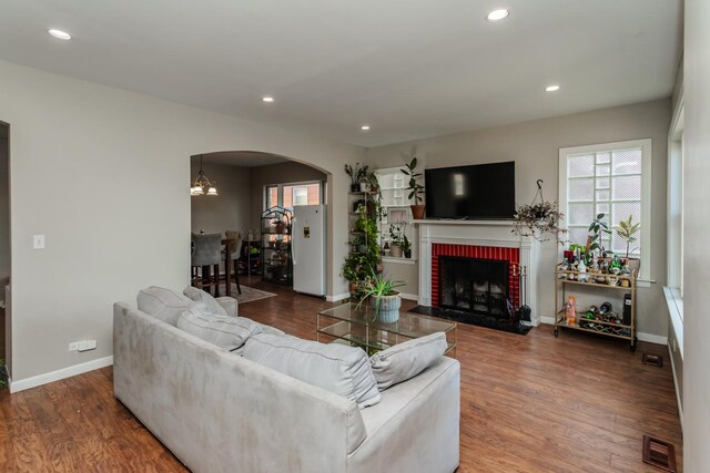 living room featuring a notable chandelier, a fireplace, and dark wood-type flooring