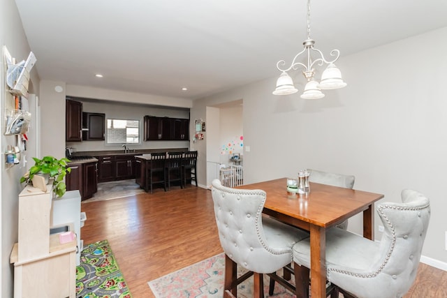 dining space with light hardwood / wood-style floors, a notable chandelier, and sink