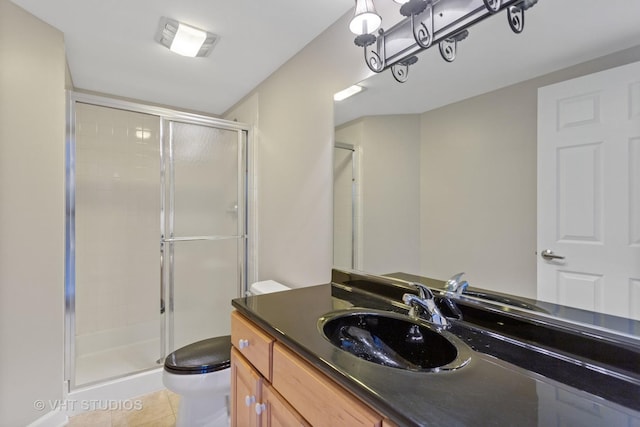 bathroom with tile patterned floors, vanity, toilet, and a shower with door