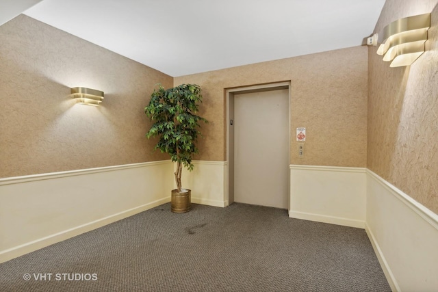 spare room with dark carpet and elevator